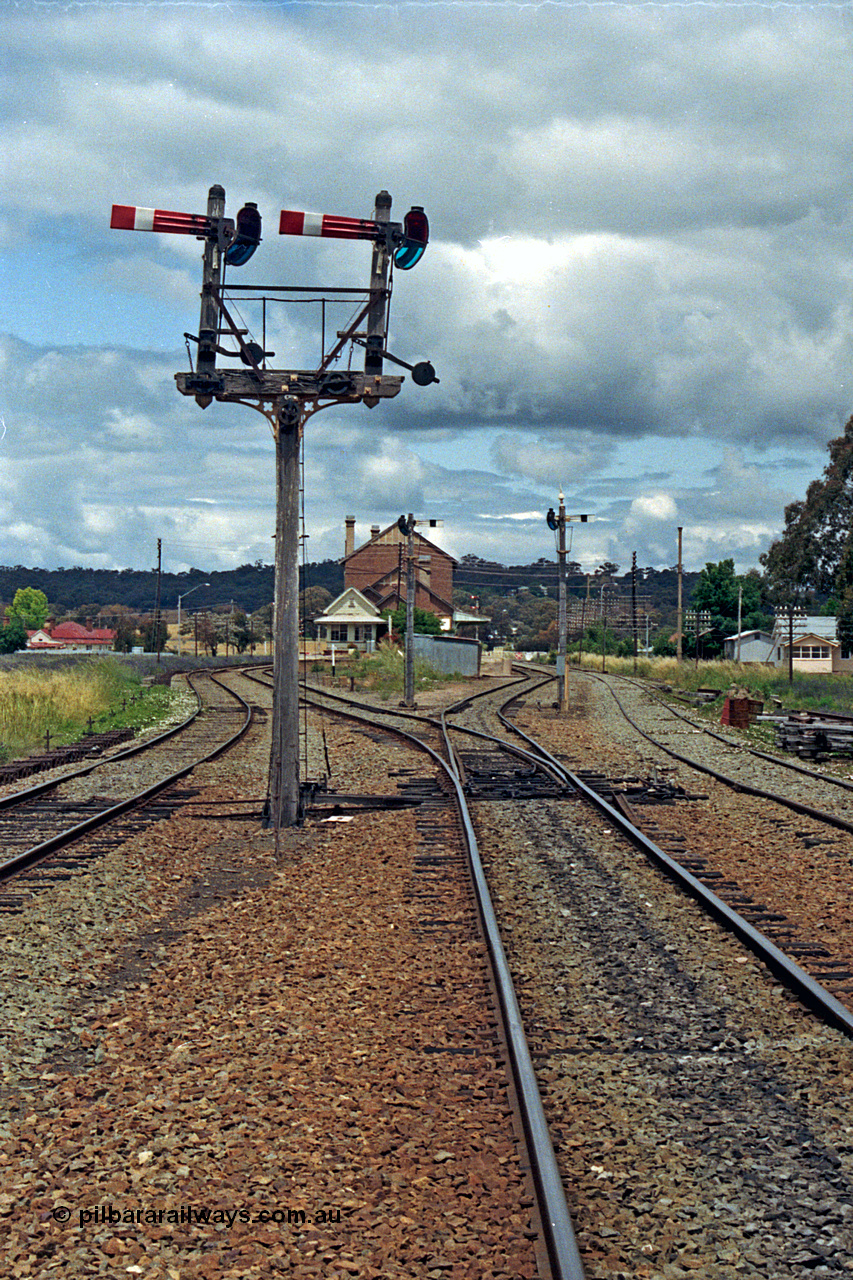 192-31
Cootamundra West, NSW, looking east in the up direction with the Loop Line on the left, Main Line lower quadrant semaphores for up movements to Main Line operated by lever 41 and South Fork to the right from lever 46, with each respective lines down semaphore signals facing away. The signal box and station are in the distance and the siding at right is the Tumut Siding. The house in the distance looks a lot like a NSWGR departmental residence.
