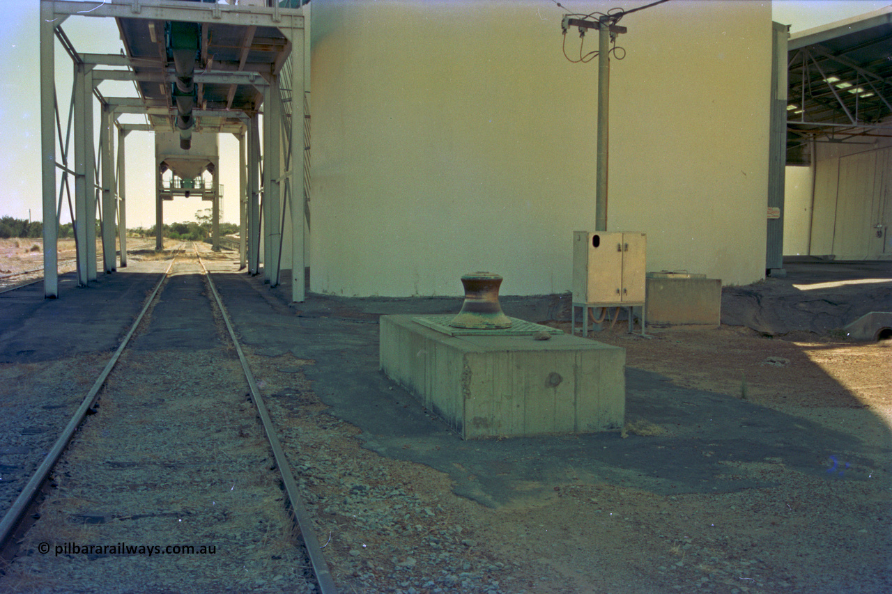 202-18
Meckering, looking west along the grain siding, capstan winch for assisting in moving grain waggons, the three loadout spouts for the concrete grain silos with the two overhead bunker loadouts visible beyond them.
