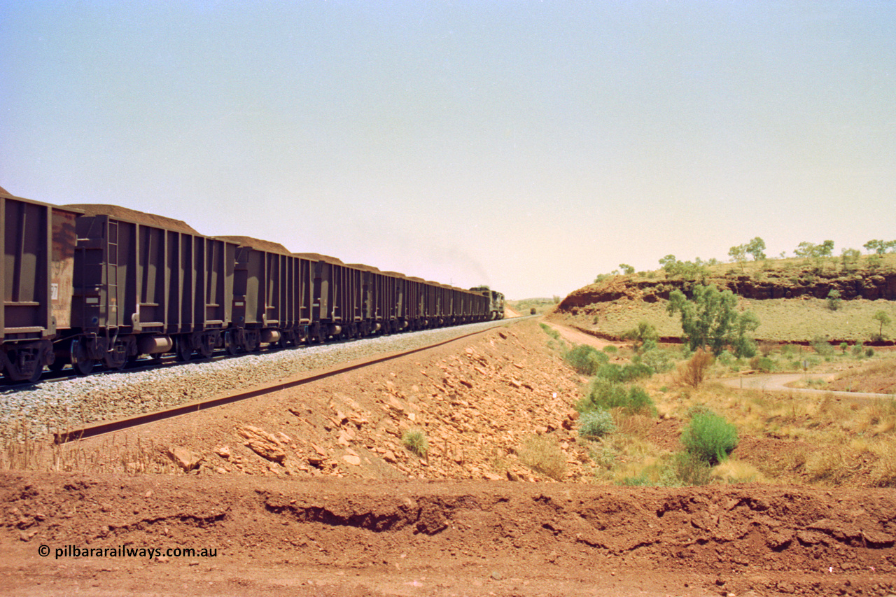 202-30
Yandi One, 307 km grade crossing sees a loaded train departing behind a CM40-8M and an CM40-8 unit with the rail grinder in the back track in the distance, the road curving around at the right goes to the Henry Walker camp.
