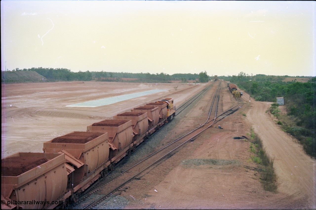 212-22
Weipa, a loaded train ex-Andoom Mine runs along the main with thirty two waggons at Lorim Point towards the dump station behind Comalco R 1001 Clyde Engineering built EMD model GT26C serial 72-752 originally numbered 1.001 and built in 1972. July 1995.
