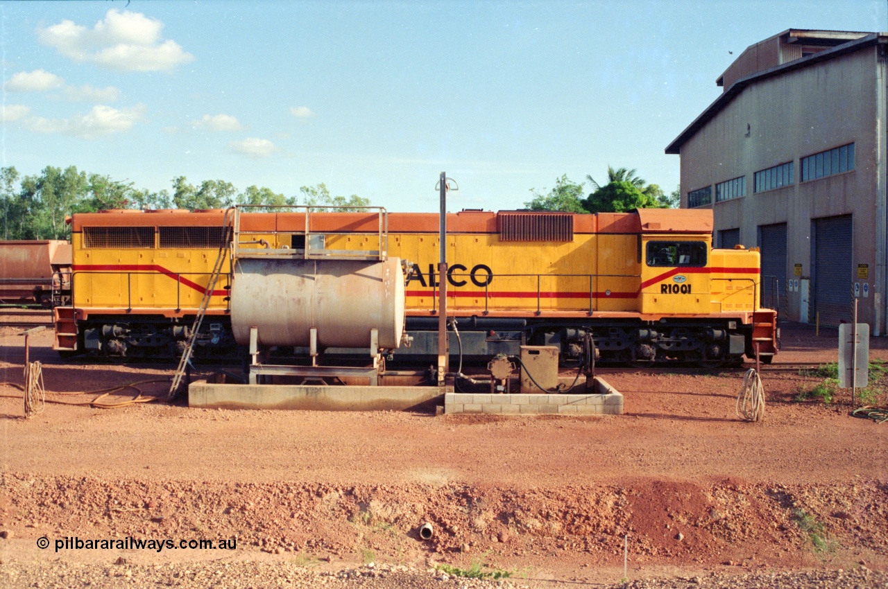 213-05
Weipa, Lorim Point fuel point looking south across the apron, Comalco R 1001 loco Clyde Engineering built EMD model GT26C serial 72-752 sits at the fuel point, items of note are these units were setup to have the long hood leading, the second 'tropical roof' and the five chime horn cut into the nose. Also noticeable, the units don't have dynamic brakes fitted so there is no brake 'blister' in the middle of the hood like you see on the GT26C models of WAGR L or VR C classes. September 1995.
Keywords: R1001;Clyde-Engineering;EMD;GT26C;72-752;1.001;Comalco;