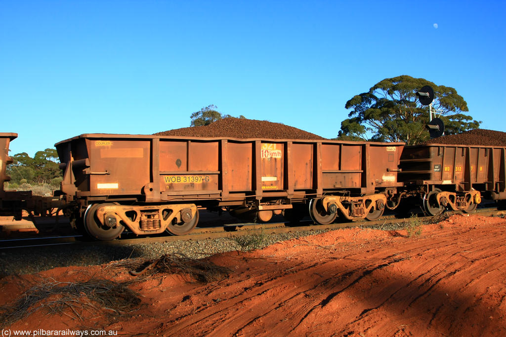 100731 02356
WOB type iron ore waggon WOB 31397 is one of a batch of twenty five built by Comeng WA between 1974 and 1975 and converted from Mt Newman high sided waggons by WAGR Midland Workshops with a capacity of 67 tons with fleet number 321 for Koolyanobbing iron ore operations. This waggon was also converted to a WSM type ballast hopper by re-fitting the cut down top section and having bottom discharge doors fitted, converted back to WOB in 1998, on loaded train 6413 at Binduli Triangle, 31st July 2010.
Keywords: WOB-type;WOB31397;Comeng-WA;WSM-type;Mt-Newman-Mining;