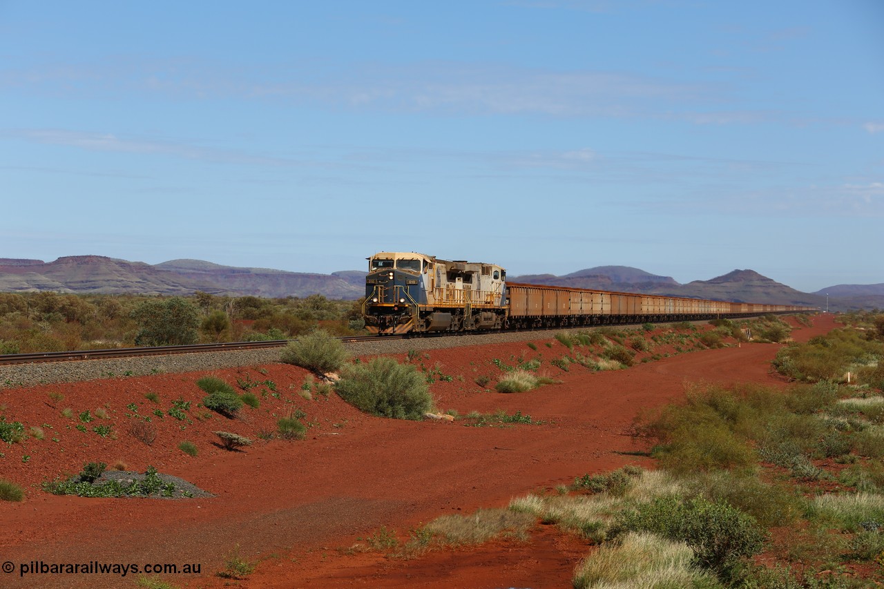 150507 8043
FMG Solomon Line, as the Nanutarra - Wittenoom Road was realigned when this line was built, this is where the western shortcut branch of the Roebourne - Wittenoom Road crosses the line before rejoining the Nanutarra Road. A loaded train behind double General Electric Dash Dash 9-44CW Co-Co locomotives, units 010 serial no. 58187 and 014 serial no. 58191 power a loaded along the straight, there are bank engines on the rear. Geodata: [url=https://goo.gl/maps/upAfsxGcMED2] -22.1617767 118.1279150 [/url].
