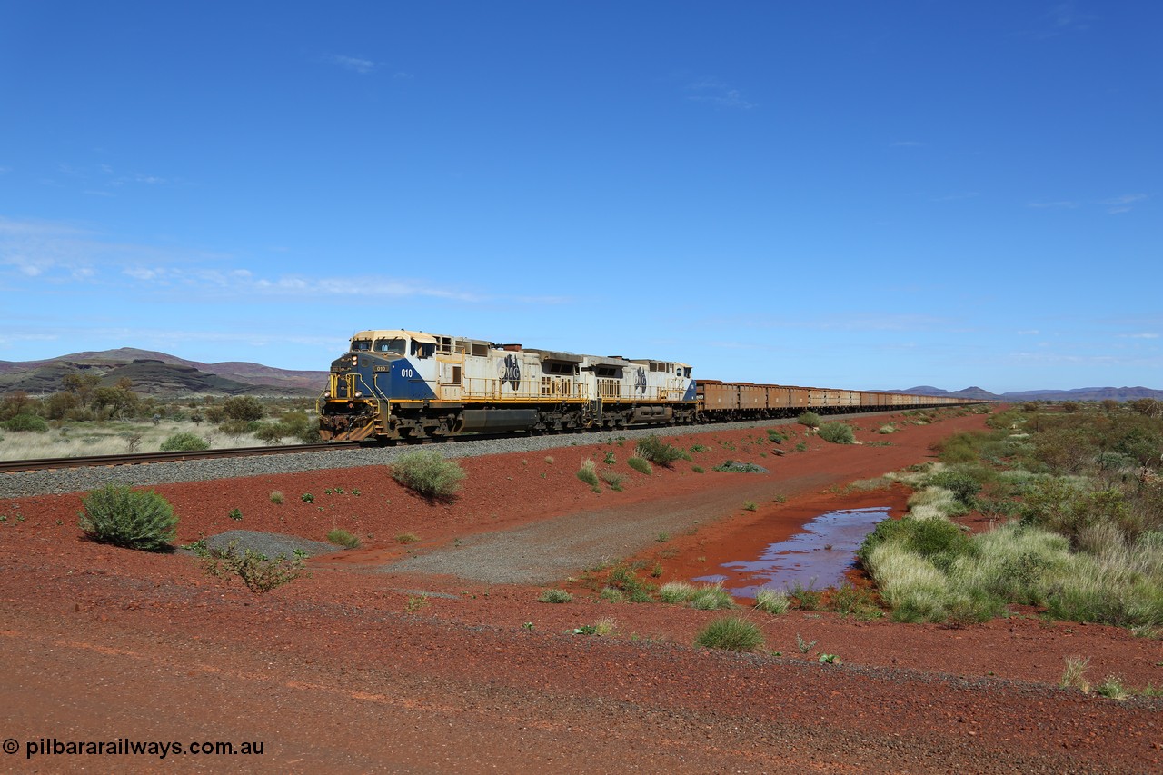 150507 8046
FMG Solomon Line, as the Nanutarra - Wittenoom Road was realigned when this line was built, this is where the western shortcut branch of the Roebourne - Wittenoom Road crosses the line before rejoining the Nanutarra Road. A loaded train behind double General Electric Dash Dash 9-44CW Co-Co locomotives, units 010 serial no. 58187 and 014 serial no. 58191 power a loaded along the straight, there are bank engines on the rear. Geodata: [url=https://goo.gl/maps/upAfsxGcMED2] -22.1617767 118.1279150 [/url].
