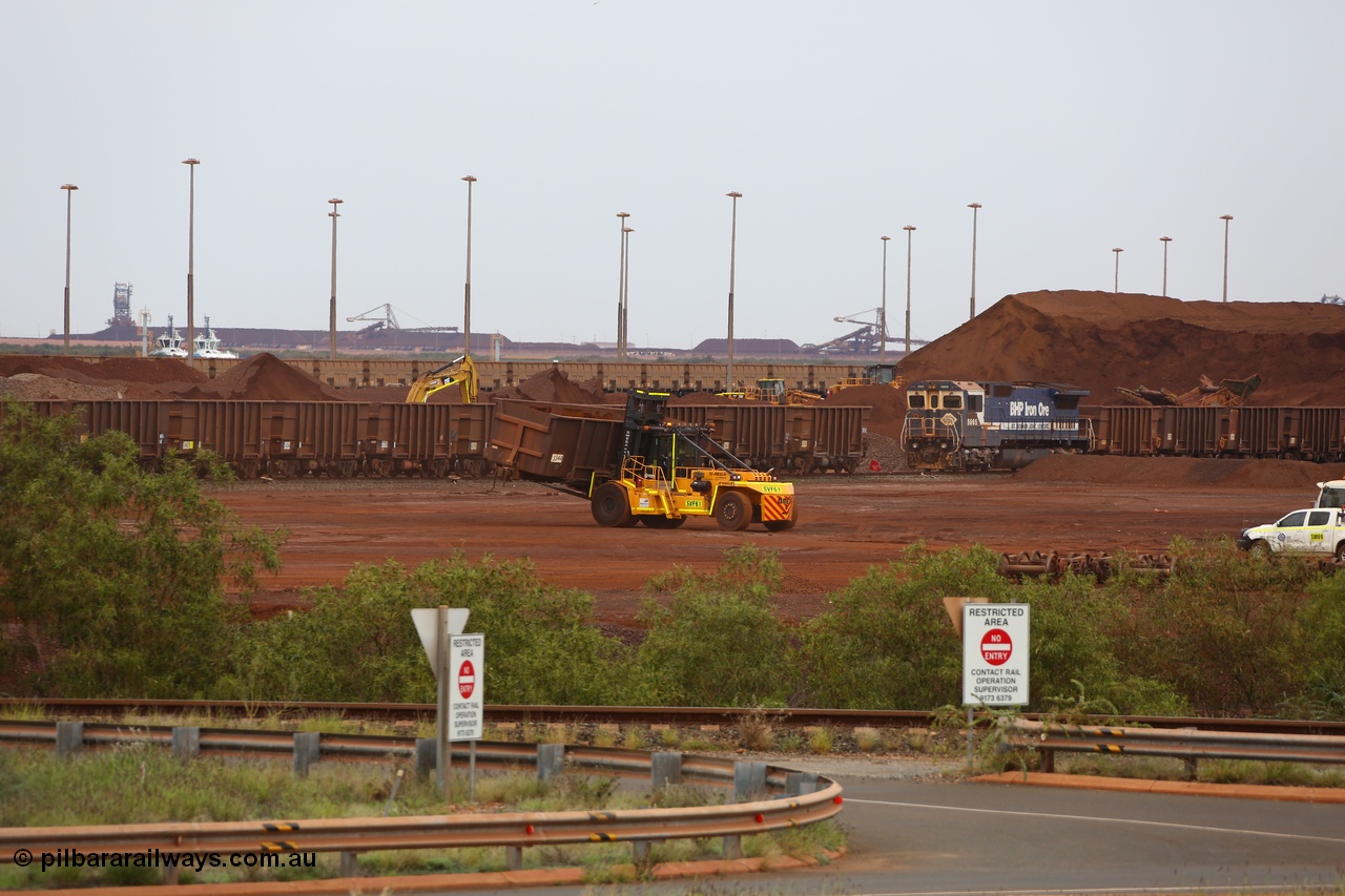 150523 8234
Nelson Point Yard, I Area, waggon scrapping by Sims Metal, a fork lift carries waggon no. 3340, one of 350 waggons built in Romania of which only about 60 made it into service, the rest rusting away in a caged embargo area out on the Broome Road until they were scrapped some years ago. There is a connection with these waggons and Lang Hancock and his former mine McCamey's Monster, now known as Jimblebar. 5665 looks on, its days also numbered.
Keywords: Arad-Romania;BHP-ore-waggon;
