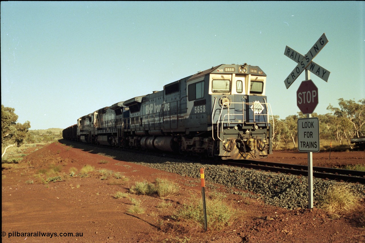 196-02
Yandi Two loaded car side of the loadout balloon loop, BHP Iron Ore CM40-8M or Dash 8 motive power in the form of 5658 'Kakogawa' serial 8412-03 / 94-149 rebuilt by Goninan as GE model CM40-8M from ALCo M636C number 5480 and two new Goninan built GE CM39-8 units 5630 'Zeus' serial 5831-09 / 88-079 and 5631 'Apollo' serial 5831-10 / 88-080 are the head end power with another two CM40-8M units mid-train. Train length is 240 waggons with a 120/120 split. Yandi Two ore stockpile and pedestal stacker boom tip visible in the background, the loadout operates via gravity and the train travels through a tunnel. May 1998.
Keywords: 5658;Goninan;GE;CM40-8M;8412-03/94-149;rebuild;AE-Goodwin;ALCo;M636C;5480;G6061-1;