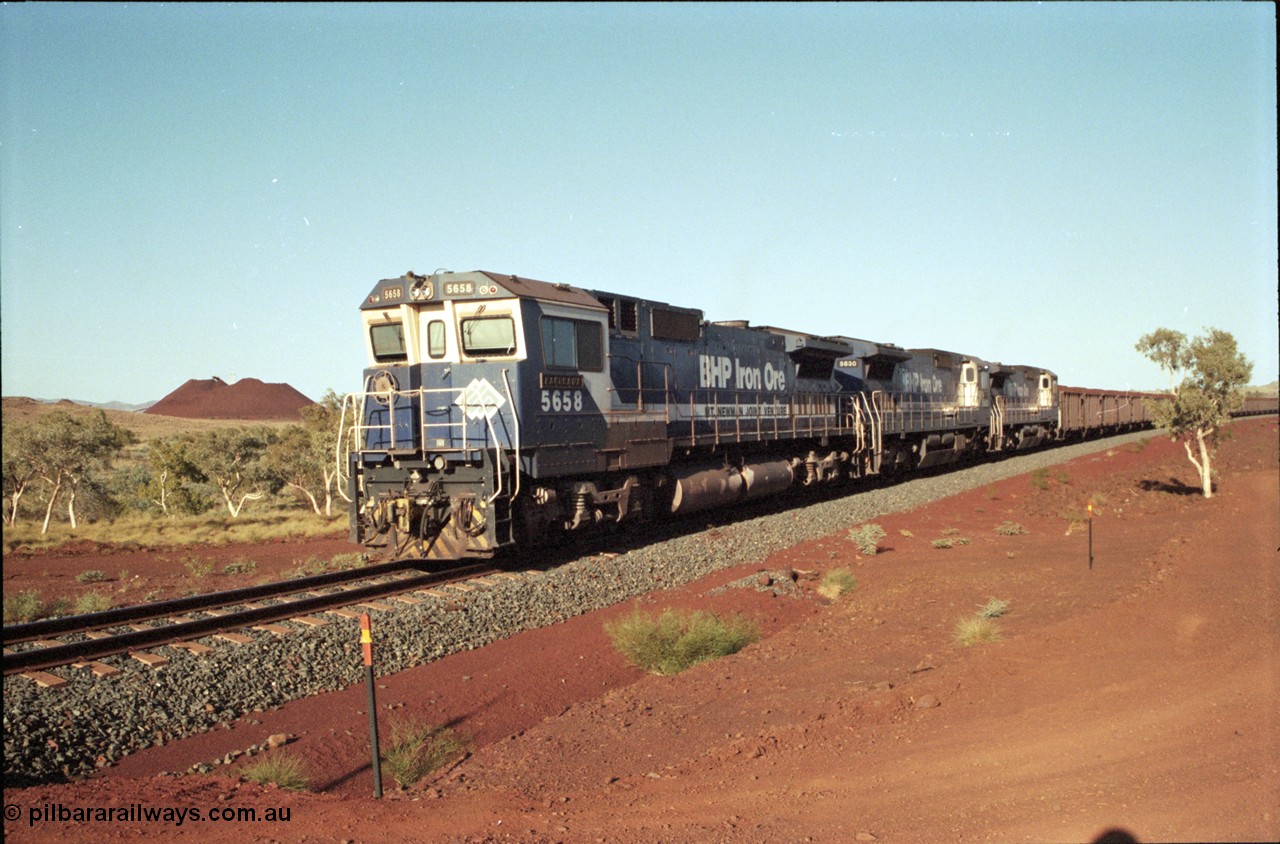 196-14
Yandi Two loaded car side of the loadout balloon loop, BHP Iron Ore CM40-8M or Dash 8 motive power in the form of 5658 'Kakogawa' serial 8412-03 / 94-149 rebuilt by Goninan as GE model CM40-8M from ALCo M636C number 5480 and two new Goninan built GE CM39-8 units 5630 'Zeus' serial 5831-09 / 88-079 and 5631 'Apollo' serial 5831-10 / 88-080 are the head end power with another two CM40-8M units mid-train. Train length is 240 waggons with a 120/120 split. Yandi Two ore stockpile and pedestal stacker boom tip visible in the background, the loadout operates via gravity and the train travels through a tunnel. May 1998.
Keywords: 5658;Goninan;GE;CM40-8M;8412-03/94-149;rebuild;AE-Goodwin;ALCo;M636C;5480;G6061-1;