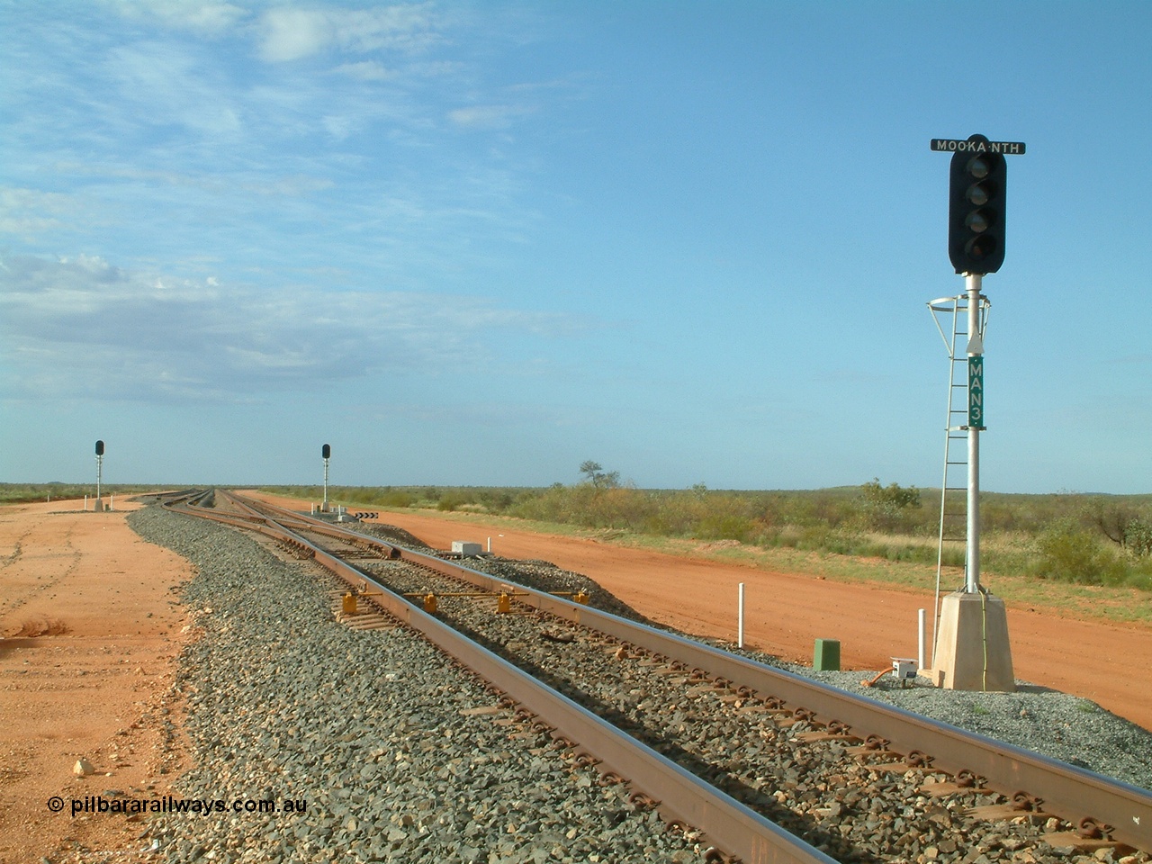 040407 075227
Mooka Siding, north end looking south past the arrival signal LED type MAN 3, DED 'dragging equipment detector' bars are visible before the turnout, passing track branching off to the left. 7th April 2004.
