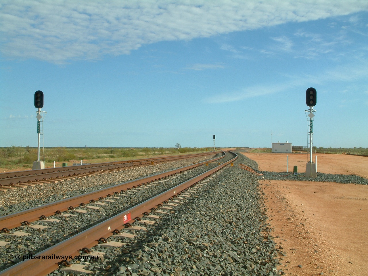 040407 075405
Mooka Siding, north end looking north, 31.4 km showing the standard layout of the track when it was single track with passing sidings, MAN 4 on the left is the mainline departure and MAN 6 in the passing track departure, all LED type. The DED 'dragging equipment detection' bars are visible along with the arrival signal and relay room. 7th April 2004.

