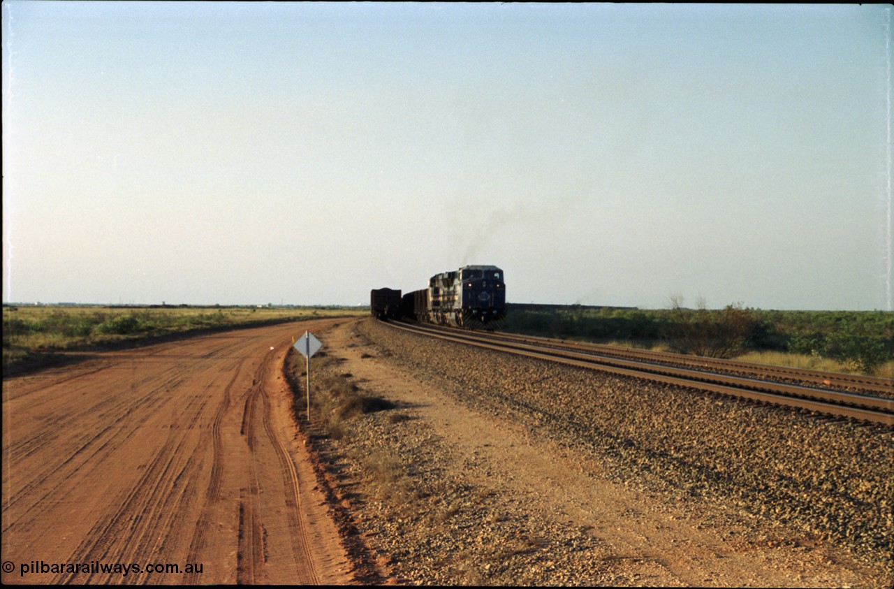 203-00
Bing Siding, an empty train behind BHP General Electric AC6000 unit 6076 'Mt Goldsworthy' serial 51068 runs around the passing track with a loaded train on the mainline.
