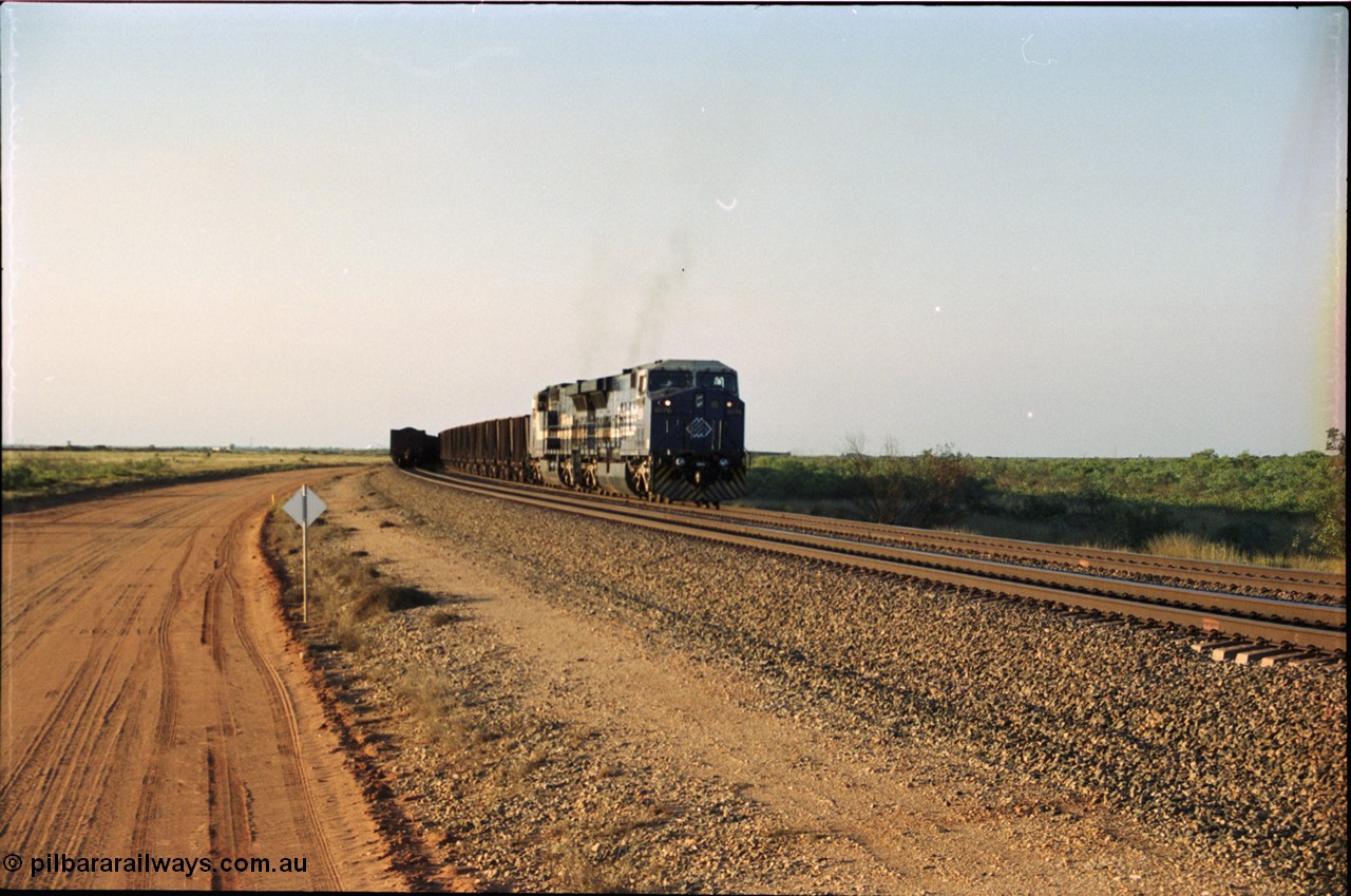 203-01
Bing Siding, an empty train behind BHP General Electric AC6000 unit 6076 'Mt Goldsworthy' serial 51068 runs around the passing track with a loaded train on the mainline.
