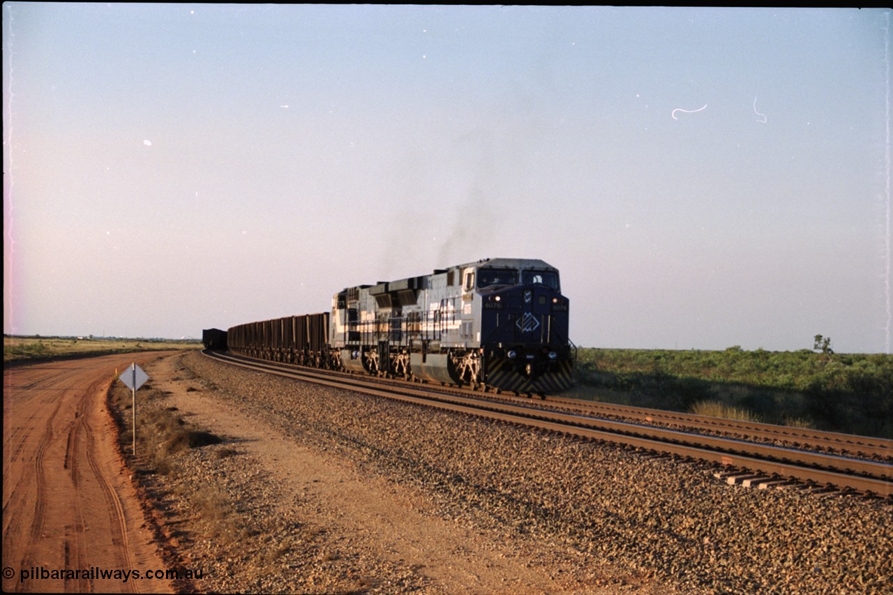 203-02
Bing Siding, an empty train behind BHP General Electric AC6000 unit 6076 'Mt Goldsworthy' serial 51068 runs around the passing track with a loaded train on the mainline.
