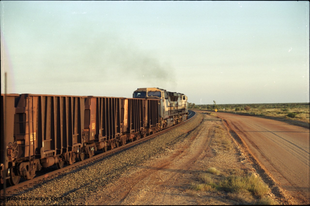 203-22
Bing Siding, empty train behind a pair of General Electric AC6000 units powers around the curve. Note the ladder on the original Comeng style waggon.
