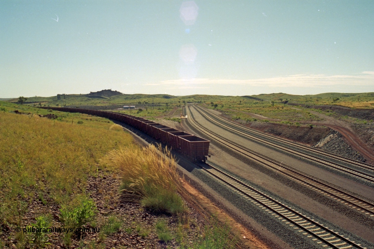218-29
Yandicoogina or HIY as Hamersley Iron identify it, located 445 km from Parker Point yard in Dampier, view looking at rear of empty train being loaded with fuel tanks and loco fuel point in middle of frame and mine stockpiles in the background.
