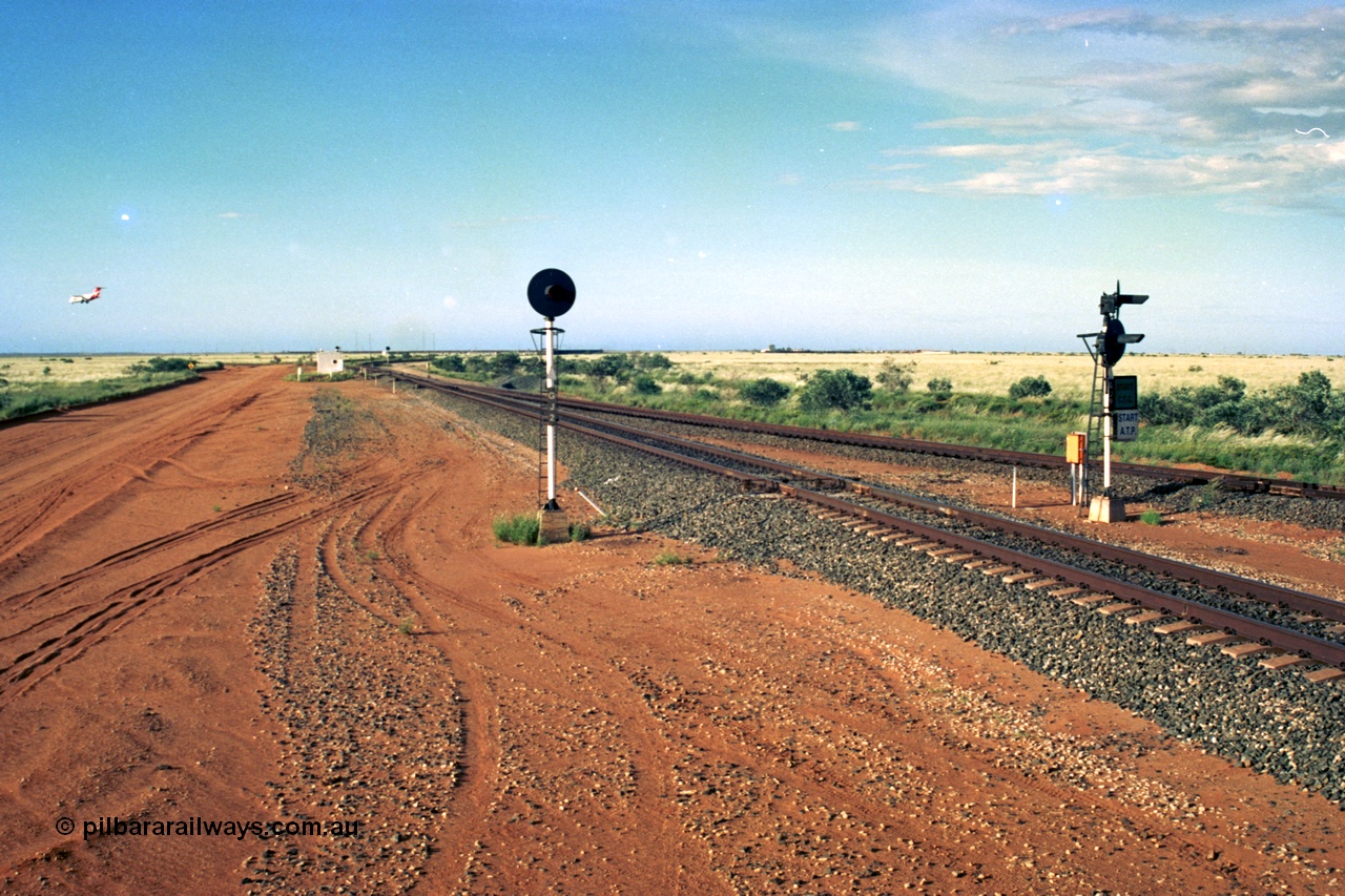 220-27
Goldsworthy Junction, an empty train on the Newman line approaches having departed Nelson Point. The line merging in from the right is the Goldsworthy line to Yarrie and Nimingarra, which can then be made out diverging to the left just after the interlocking room in front of the train.
