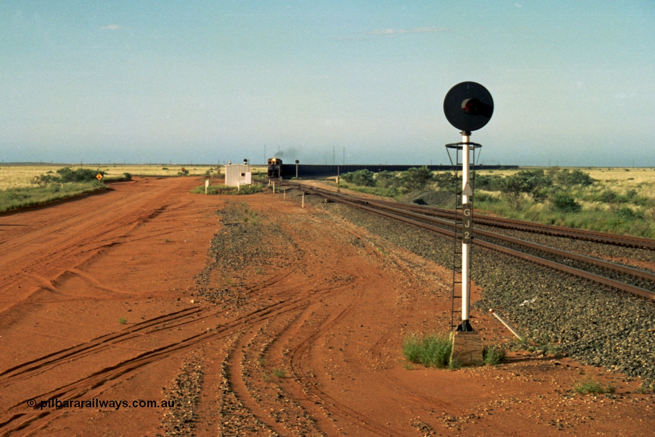 220-28
Goldsworthy Junction, an empty train on the Newman line approaches having departed Nelson Point. The line merging in from the right is the Goldsworthy line to Yarrie and Nimingarra, which can then be made out diverging to the left just after the interlocking room in front of the train.
