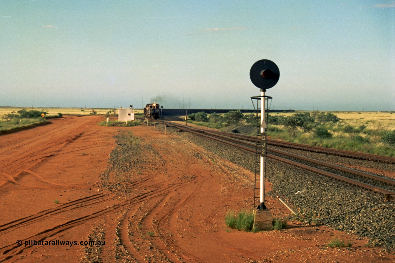 220-29
Goldsworthy Junction, an empty train on the Newman line approaches having departed Nelson Point. The line merging in from the right is the Goldsworthy line to Yarrie and Nimingarra, which can then be made out diverging to the left just after the interlocking room in front of the train.
