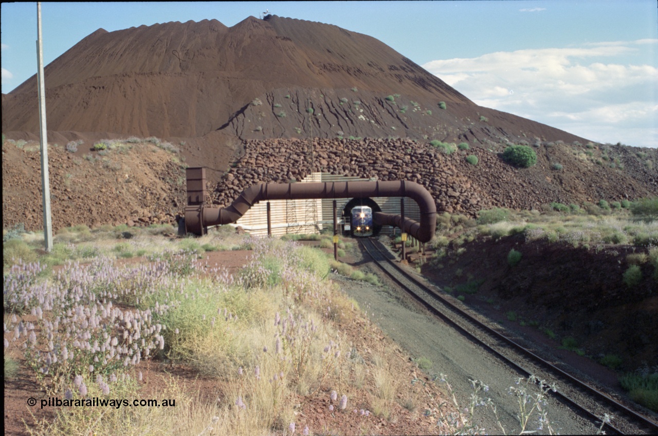 221-20
Yandi One mine loadout balloon loop, General Electric AC6000 class emerges from the loadout portal as it leads a train through the loading vaults, the dust extraction ducting is also visible and the plant stacker can been seen at the very top of the stockpile.
Keywords: GE;AC6000;51062-9;
