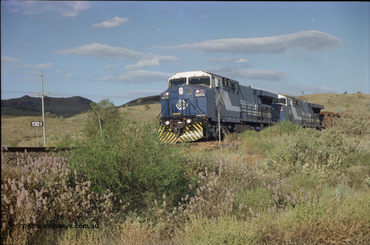 221-30
Yandi One mine loadout balloon loop, near new General Electric AC6000 unit 6074 serial 51066 leads sister unit 6071 serial 51063 at the Y312.1 km crossing while controlling a train being loaded.
Keywords: 6074;GE;AC6000;51066;