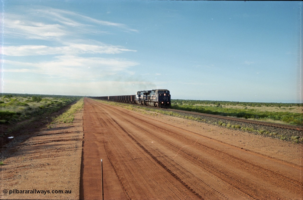 225-17
At the 24.1 km grade crossing on the BHP Newman line, the afternoon departure for Yandi mine heads south behind the standard double General Electric AC6000 units with GE Erie built 6074 serial 51066 leading sister unit 6075 with another AC6000 unit mid-train. This was before the units were named. [url=https://goo.gl/maps/qGkyfiuy6212]GeoData[/url].
Keywords: 6074;GE;AC6000;51066;