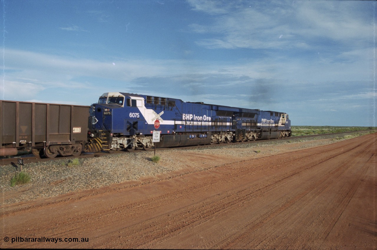 225-21
At the 24.1 km grade crossing on the BHP Newman line, the afternoon departure for Yandi mine heads south behind the standard double General Electric AC6000 units with GE Erie built 6075 serial 51067 second unit to lead sister unit 6074 with another AC6000 unit mid-train. This was before the units were named. [url=https://goo.gl/maps/qGkyfiuy6212]GeoData[/url].
Keywords: 6075;GE;AC6000;51067;
