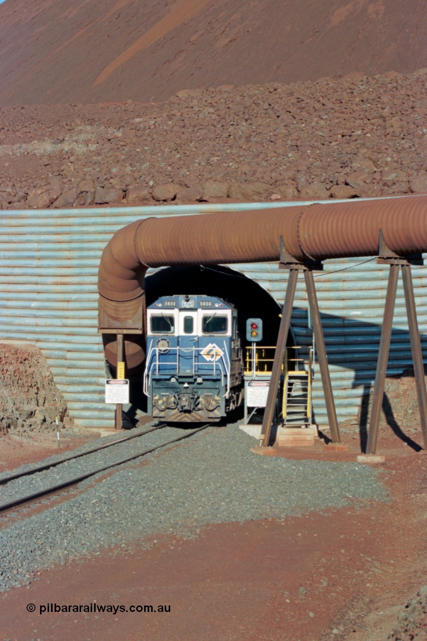 229-15
Yandi Two loadout, looking at the exit portal of the tunnel as Goninan rebuild CM40-8M GE unit 5650 'Yawata' serial 8412-07 / 93-141 drags a loading through at 1.2 km/h, the massive pile of ore is gravity fed into the waggons via two sets of hydraulic chutes, the red and amber lights control access through the tunnel and the steel pipe is for dust extraction. [url=https://goo.gl/maps/jmtnauf76Zq]GeoData[/url].
Keywords: 5650;Goninan;GE;CM40-8M;8412-07/93-141;rebuild;AE-Goodwin;ALCo;M636C;5481;G6061-2;