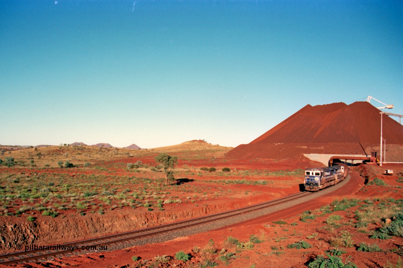 229-24
Yandi Two loadout exit side, as Goninan rebuild CM40-8M GE unit 5650 'Yawata' serial 8412-07 / 93-141 and sister unit drag a loading train at 1.2 km/h, the massive pile of ore is gravity fed into the waggons via two sets of hydraulic chutes, the original pedestal radial stacker is visible above the ore along with the extraction fan, on the left the mid-train remotes can just be made out. [url=https://goo.gl/maps/KQ3dQNrTwd42]GeoData[/url].
Keywords: 5650;Goninan;GE;CM40-8M;8412-07/93-141;rebuild;AE-Goodwin;ALCo;M636C;5481;G6061-2;