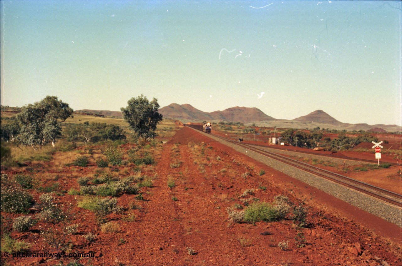 230-02
Yandi Two switch looking east with the Three Sisters forming the background. Empty BHP train heading for the balloon loop for loading, grade crossing is the YT 311.5 km. Geodata [url=https://goo.gl/maps/DcycDGojcBt] -22.713725, 119.055762 [/url].
