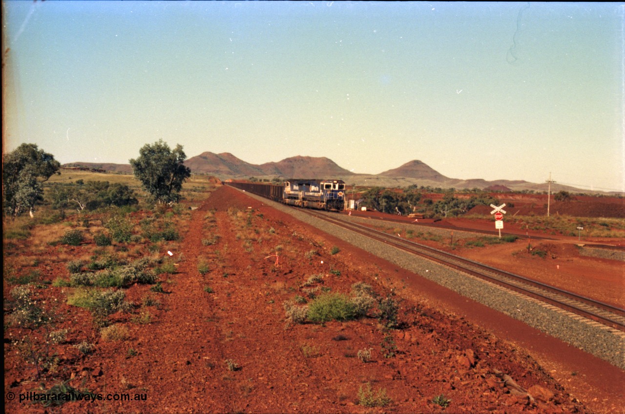230-06
Yandi Two switch looking east with the Three Sisters forming the background. Empty BHP train heading for the balloon loop for loading, grade crossing is the YT 311.5 km. Geodata [url=https://goo.gl/maps/DcycDGojcBt] -22.713725, 119.055762 [/url].
