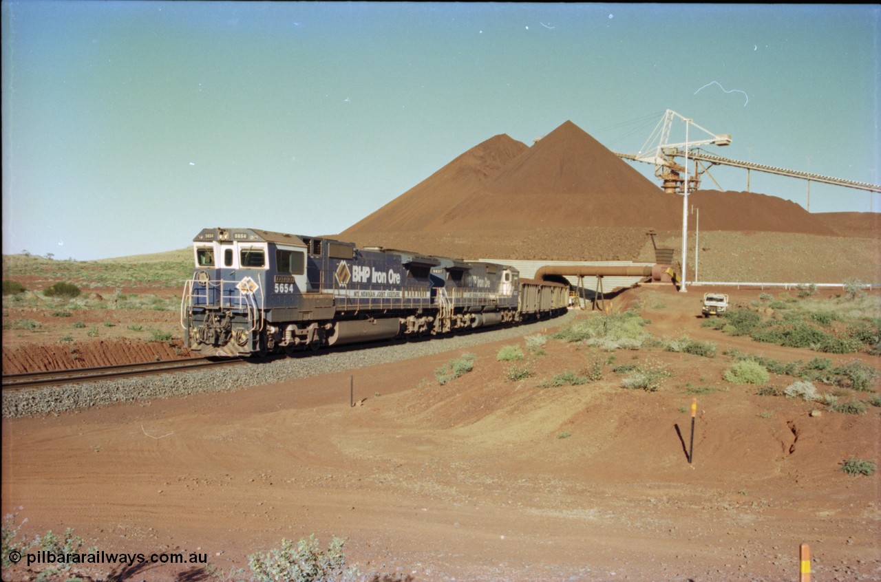 230-26
Yandi Two balloon loop, view of the stockpile area and pedestal stacker, train being loaded at 1.2 km/h behind two Goninan GE CM40-8M rebuilds from different ALCo builders. 5654 'Kashima' serial 8412-11/93-145 is from Comeng ALCo M636 unit 5493 while 5637 'De Grey' serial 8181-01/92-123 is from an AE Goodwin ALCo C636 unit 5456. Geodata [url=https://goo.gl/maps/h68ia1caJvL2] -22.718338, 119.039909 [/url].
Keywords: 5654;Goninan;GE;CM40-8M;8412-11/93-145;rebuild;Comeng-NSW;ALCo;M636C;5493;C6084-9;