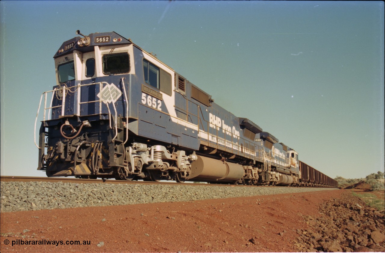231-26
Yandi Two balloon loop, BHP Iron Ore 5652 'Villanueva' serial 8412-09 / 93-143 an Goninan WA rebuild CM40-8M GE unit loads a train at 1.2 km/h with second unit 5650. [url=https://goo.gl/maps/3vQHZqBXNa32]GeoData[/url].
Keywords: 5652;Goninan;GE;CM40-8M;8412-09/93-143;rebuild;AE-Goodwin;ALCo;M636C;5482;G6061-3;