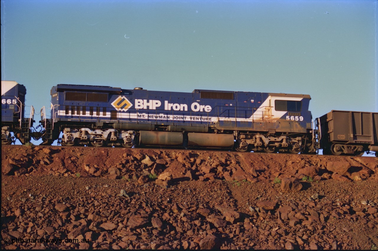 232-06
Yandi One balloon loop, mid-train remote units of train no. 1718 which is partway through loading, BHP Iron Ore unit 5659 'Kobe' serial 8412-04 / 94-150 leads cabless unit 5665, both are Goninan rebuild CM40-8M GE units, 59 is still in the teal and marigold logo livery. 3rd of February 1997. [url=https://goo.gl/maps/JhTwdFuTRZo]GeoData[/url].
Keywords: 5659;Goninan;GE;CM40-8M;8412-04/94-150;rebuild;AE-Goodwin;ALCo;M636C;5483;G6061-4;