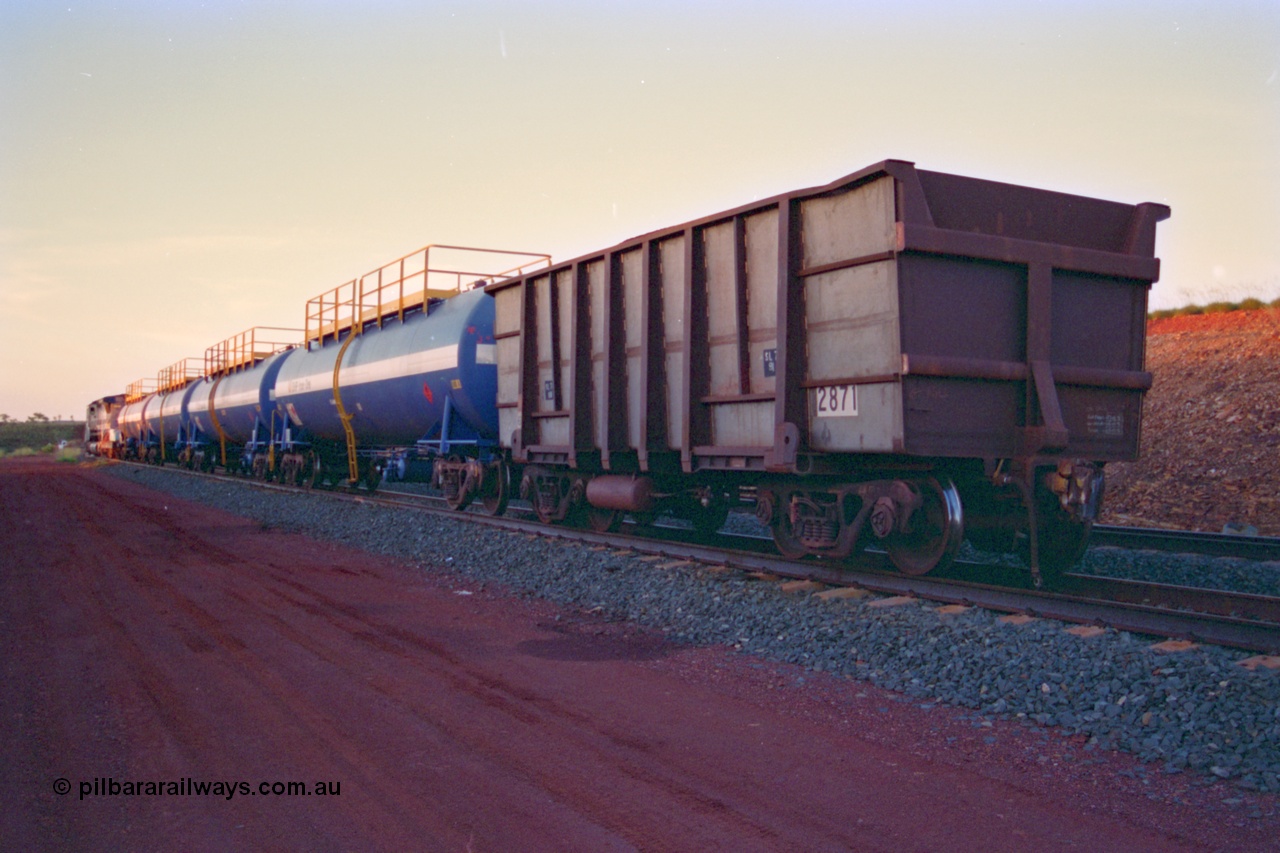 232-19
Yandi One backtrack, following a cyclone shutdown of the mainline and severe flooding around Yandi a 'mixed' freight train was operated to Yandi to deliver food, mail and diesel fuel to the mine and camp. Here BHP Iron Ore loaded Comeng WA built ore waggon 2871 has been re-sheeted with 3CR12 stainless steel side walls. February 1997. [url=https://goo.gl/maps/6c1WFqjYSg42]GeoData[/url].
Keywords: 2871;Comeng-WA;