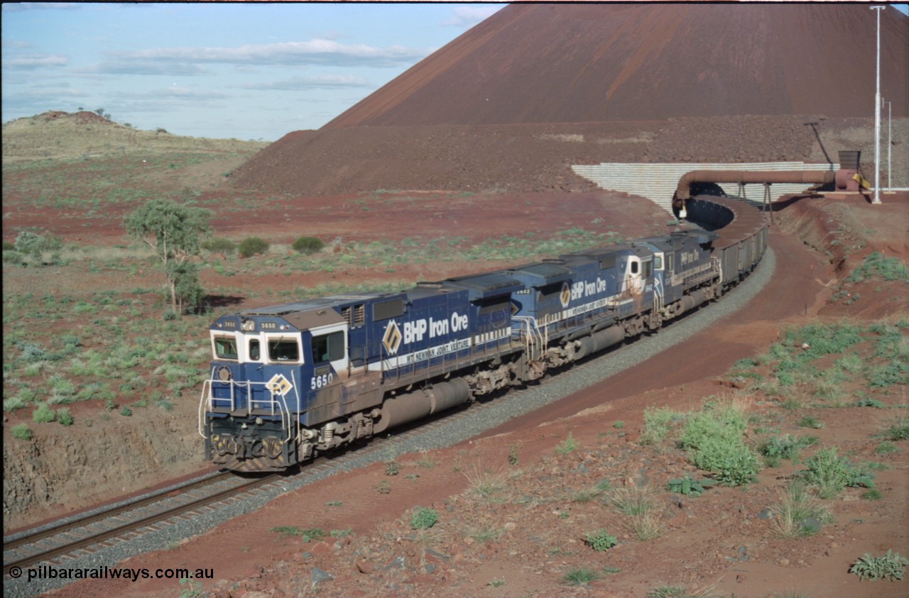 233-27
Yandi Two loaded car side of load-out tunnel, a loading train lead by BHP Iron Ore's Goninan rebuild CM40-8M GE unit 5650 'Yawata' serial 8412-07 / 93-141 as it drags the train through at 1.2 km/h with assistance from two sister units. [url=https://goo.gl/maps/gXRbfYH9U482]GeoData[/url].
Keywords: 5650;Goninan;GE;CM40-8M;8412-07/93-141;rebuild;AE-Goodwin;ALCo;M636C;5481;G6061-2;