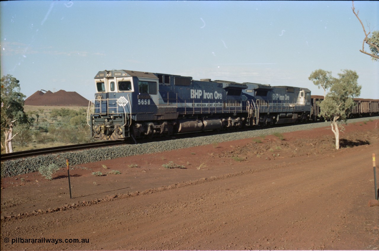 234-26
Yandi Two, BHP Iron Ore Goninan rebuild CM40-8M GE unit 5658 'Kakogawa' serial 8412-03 / 94-149 on the front of a 240 waggon loaded train, this configuration was trialled for a time with two Dash 8 locos, 120 waggons, Dash 8, 120 waggons and Dash 8. View looking from 5658 back to the ore stockpile at the loadout. Circa 1998.
Keywords: 5658;Goninan;GE;CM40-8M;8412-03/94-149;rebuild;AE-Goodwin;ALCo;M636C;5480;G6061-1;