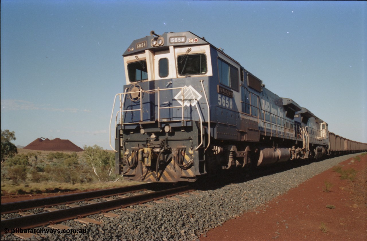 234-27
Yandi Two, BHP Iron Ore Goninan rebuild CM40-8M GE unit 5658 'Kakogawa' serial 8412-03 / 94-149 on the front of a 240 waggon loaded train, this configuration was trialled for a time with two Dash 8 locos, 120 waggons, Dash 8, 120 waggons and Dash 8. Cab front on view. Circa 1998.
Keywords: 5658;Goninan;GE;CM40-8M;8412-03/94-149;rebuild;AE-Goodwin;ALCo;M636C;5480;G6061-1;