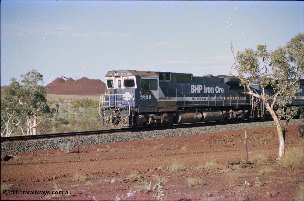 234-31
Yandi Two, BHP Iron Ore Goninan rebuild CM40-8M GE unit 5658 'Kakogawa' serial 8412-03 / 94-149 on the front of a 240 waggon loaded train, this configuration was trialled for a time with two Dash 8 locos, 120 waggons, Dash 8, 120 waggons and Dash 8. View looking from 5658 back to the ore stockpile at the loadout. Circa 1998.
Keywords: 5658;Goninan;GE;CM40-8M;8412-03/94-149;rebuild;AE-Goodwin;ALCo;M636C;5480;G6061-1;