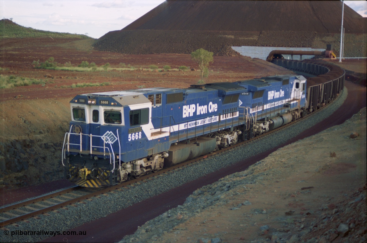 239-33
Yandi Two, train loading is under way with a pair of Goninan rebuild units, CM40-8MEFI unit 5668 'Dunkirk' serial 8412-01/95-159 and CM40-8M unit 5644 'Kangan' serial 8281-09/92-133. The lead unit was originally Comeng NSW built ALCo M636 5489 serial C6084-5, while second unit 5644 was originally a AE Goodwin built ALCo M636 5471 serial G6047-3.
