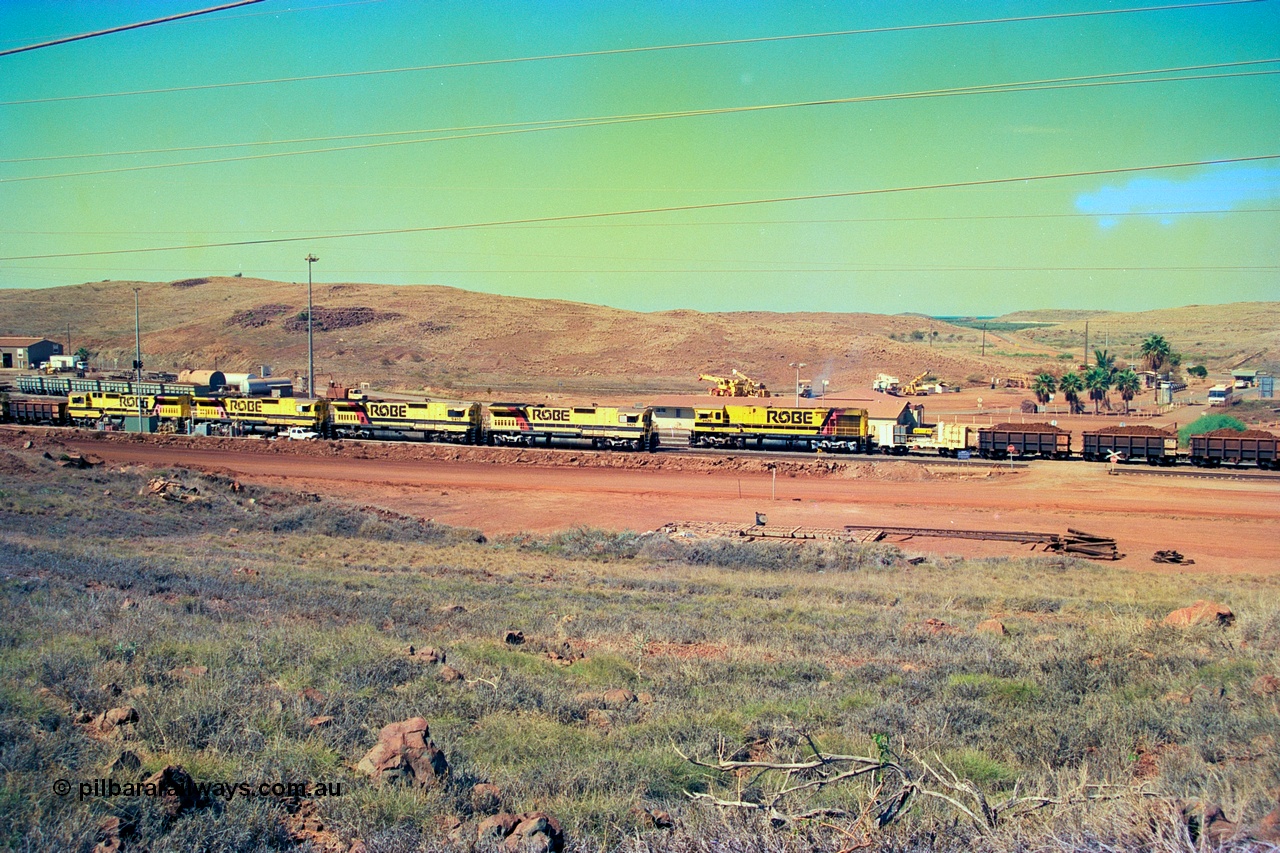 247-20
Cape Lambert yard view with Robe River Comeng WA ALCo Schenectady NY model rebuild C636R unit 9426 dragging a loaded 101 waggon rake from the South Yard across Bells Crossing while a brace of four Goninan CM40-8M GE rebuilds wait at the fuel point for a departure with an empty train. Approximate location of photo is [url=https://goo.gl/maps/TvJoLDjReJ2xoob69]here[/url]. 22nd May 2002.
Keywords: 9426;Comeng-WA;C636R;WA143-1;rebuild;ALCo;Schenectady-NY;C636;Conrail;6782;3499-3;