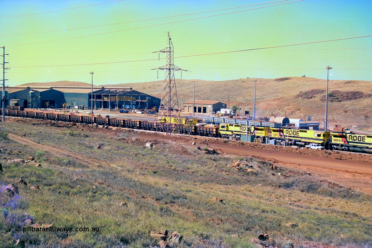 247-24
Cape Lambert overview of the fuel point, with a brace of four Goninan WA CM40-8M GE rebuilds finishing up refuelling before departing with another empty train as a loaded rake is dragged to the dumper behind them. The workshops are to the left of the picture. Where I'm standing to take the picture is now all stockpile. Approximate location of photo is [url=https://goo.gl/maps/B9F4estGGPbd2GrB6]here[/url]. 22nd May 2002.
