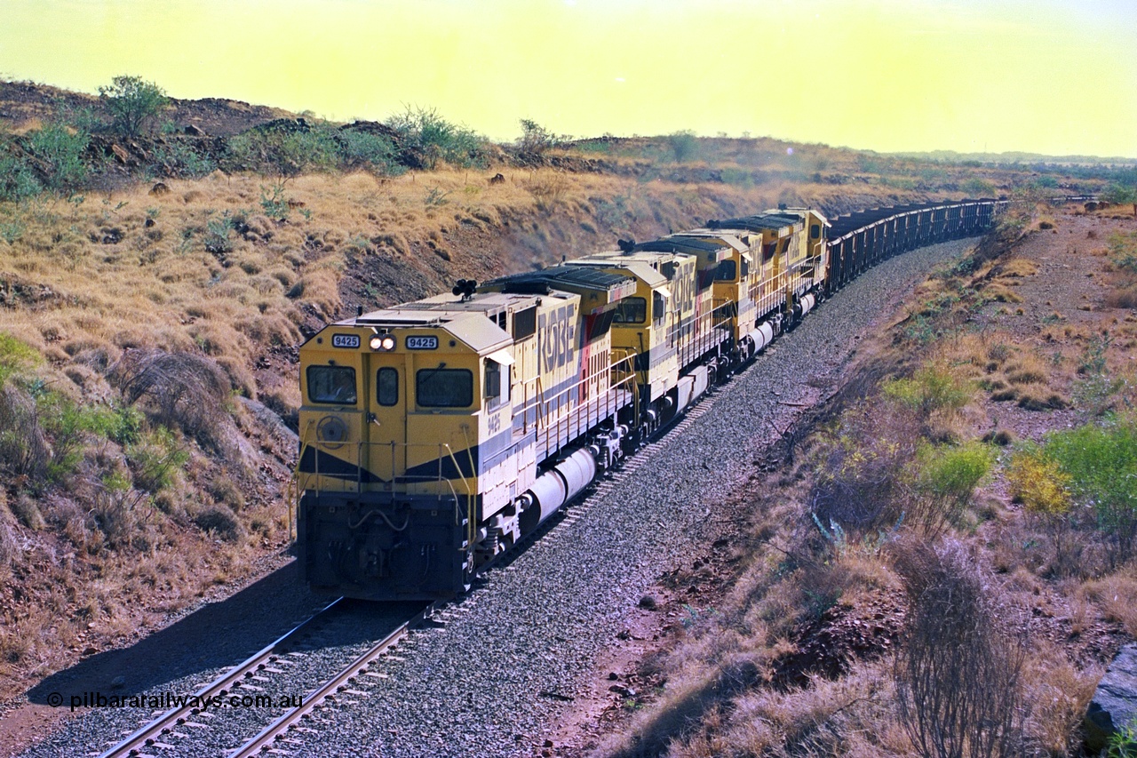 247-32
Near Cooya Pooya at the 37.5 km on the Robe River Cape Lambert line an empty train is about to pass under the town water supply pipeline and pass through Lockyer Gap behind the standard Robe power of quad CM40-8M or Dash 8 locomotives led by 9425 which is a Goninan WA ALCo to GE rebuild CM40-8M with serial 6266-8 / 89-85 from August 1989 riding on Hi-Ad bogies and was originally an AE Goodwin built M636 ALCo serial C-6041-4 and built new for Mt Newman Mining (later BHP Iron Ore) in April 1970 and numbered 5468, sold to Robe and delivered by road 17th August 1982. Location is [url=https://goo.gl/maps/nLyndU6bg2HA5SZX6]here[/url].22nd May 2002.
Keywords: 9425;Goninan;GE;CM40-8M;6266-8/89-85;rebuild;AE-Goodwin;ALCo;M636;G-6041-4;