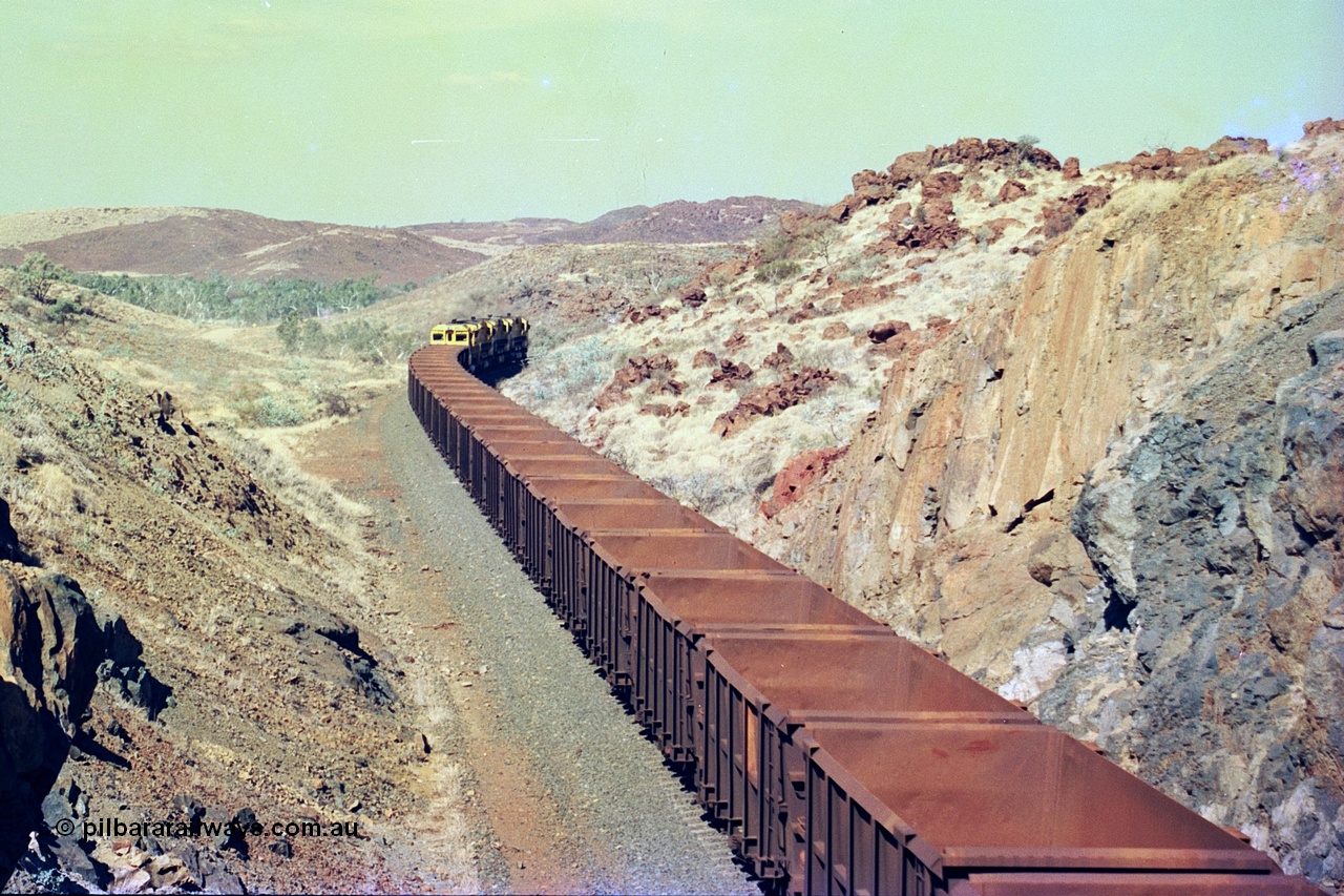 247-37
Near Cooya Pooya at the 37.5 km on the Robe River Cape Lambert line an empty train passes under the town water supply pipeline and pass through Lockyer Gap behind the standard Robe power of quad CM40-8M or Dash 8 locomotives led by 9425 with 9410, 9420 and last unit 9414 which is a Goninan WA ALCo to GE rebuild CM40-8M with serial 8206-11 / 91-124 from November 1991 riding on Dofasco bogies and was originally an AE Goodwin built M636 ALCo built new for Robe in December 1971 and numbered 262.005, later numbered 1714. Location is [url=https://goo.gl/maps/nLyndU6bg2HA5SZX6]here[/url].22nd May 2002.
