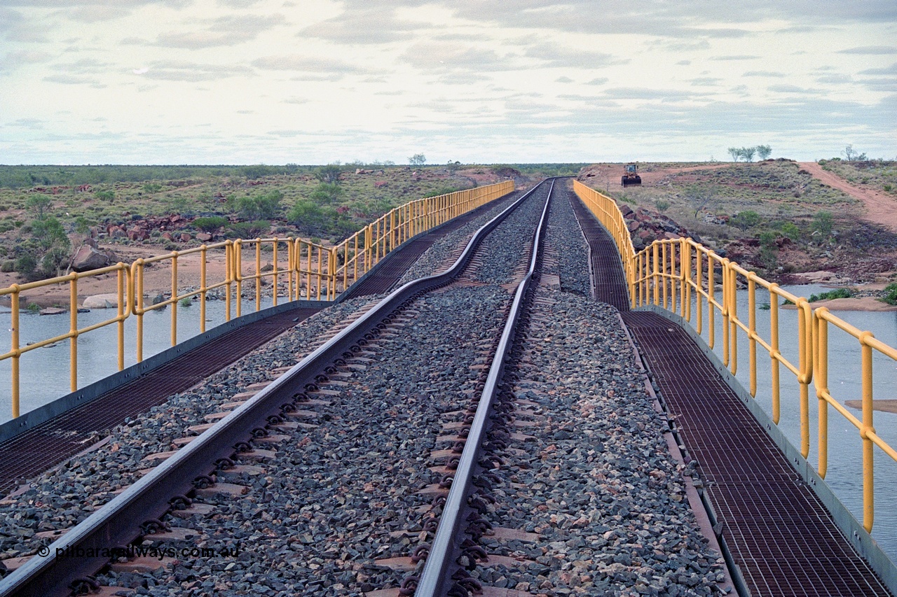 249-05
Yule River bridge looking north from the 160 km on the BHP mainline. The third pier from the southern end was undermined by flood waters from Tropical Cyclone John in December 1999. The rail line was closed for two weeks while repairs were effected. Approximate [url=https://goo.gl/maps/phCWr8u1xnuBdzwj6]location[/url].
