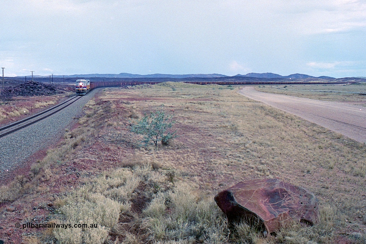 249-28
A loaded Hamersley Iron train runs across the plains north of Dugite Siding near the 70 km as it nears the destination of its cargo behind the standard pair of GE built Dash 9-44CW locomotives 7084 serial 47763 and 7079 serial 47758 both in the original Pepsi Can livery. Approximate [url=https://goo.gl/maps/UUfj15vTkvBaPCaw8]location[/url]. 18th December 1999.
Keywords: 7084;GE;Dash-9-44CW;47763;