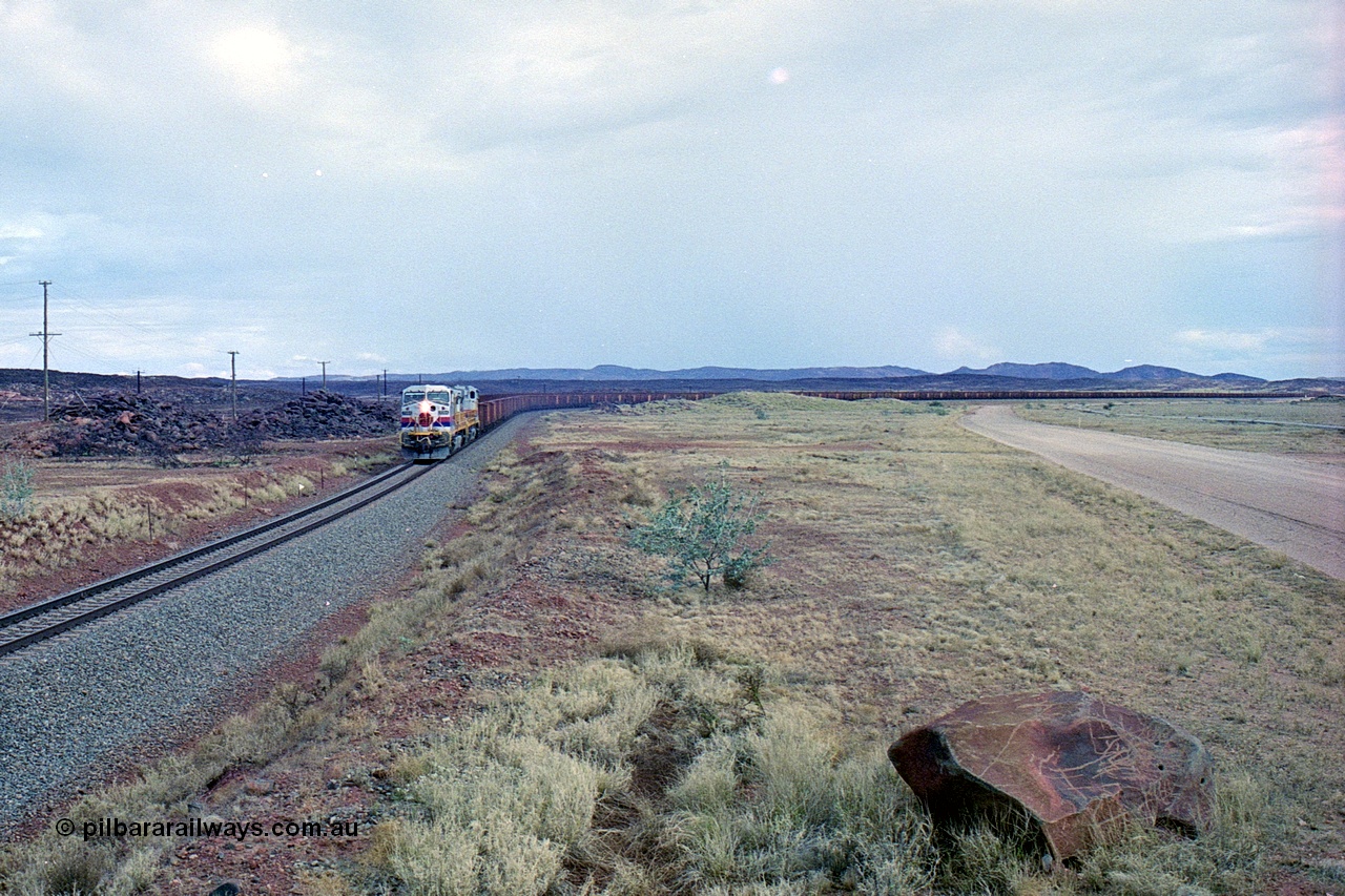 249-29
A loaded Hamersley Iron train runs across the plains north of Dugite Siding near the 70 km as it nears the destination of its cargo behind the standard pair of GE built Dash 9-44CW locomotives 7084 serial 47763 and 7079 serial 47758 both in the original Pepsi Can livery. Approximate [url=https://goo.gl/maps/UUfj15vTkvBaPCaw8]location[/url]. 18th December 1999.
Keywords: 7084;GE;Dash-9-44CW;47763;