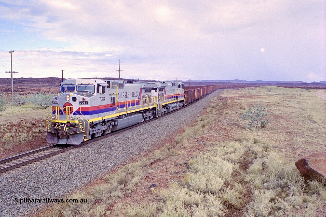 249-31
A loaded Hamersley Iron train runs across the plains north of Dugite Siding near the 70 km as it nears the destination of its cargo behind the standard pair of GE built Dash 9-44CW locomotives 7084 serial 47763 and 7079 serial 47758 both in the original Pepsi Can livery. Approximate [url=https://goo.gl/maps/UUfj15vTkvBaPCaw8]location[/url]. 18th December 1999.
Keywords: 7084;GE;Dash-9-44CW;47763;