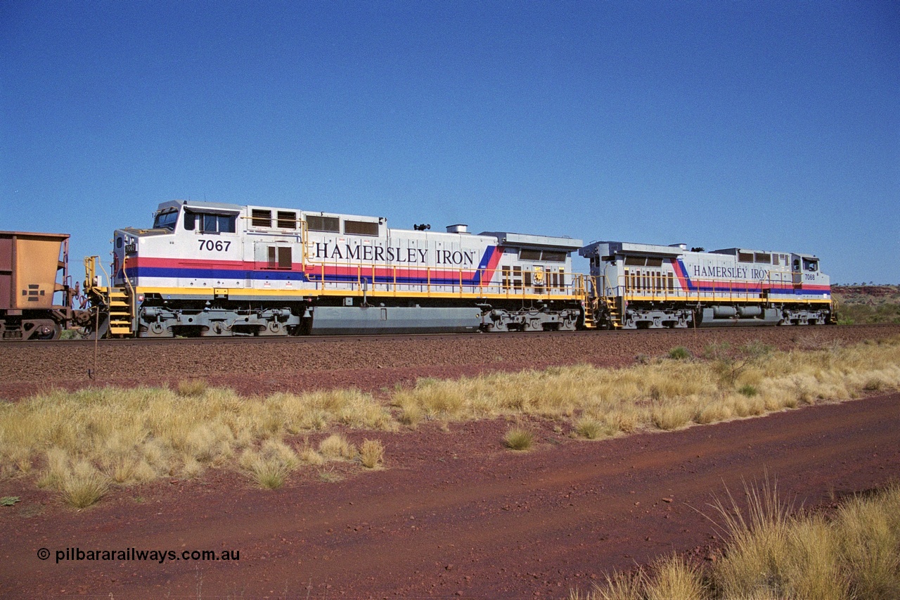 250-06
Pelican Siding on the Hamersley Iron Tom Price line about the 208 km with an empty train behind the standard pairing of two General Electric built 9-44CW units 7068 serial 47747 and 7067 serial 47746 stand on the loop or passing track for a meet with a loaded train. 21st October 2000.
Keywords: 7067;GE;Dash-9-44CW;47746;