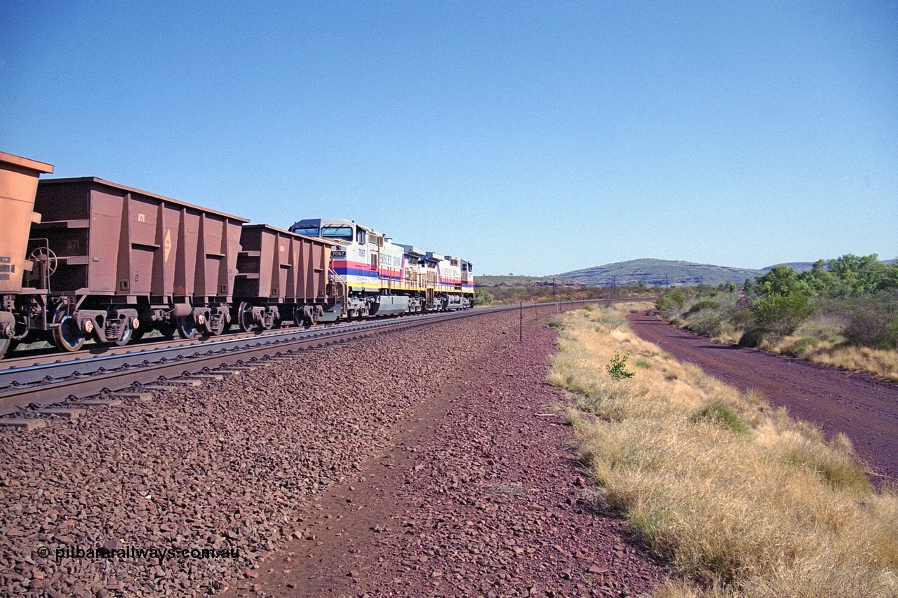 250-09
Pelican Siding on the Hamersley Iron Tom Price line about the 208 km with an empty train behind the standard pairing of two General Electric built 9-44CW units 7068 serial 47747 and 7067 serial 47746 stand on the loop or passing track for a meet with a loaded train. 21st October 2000.
