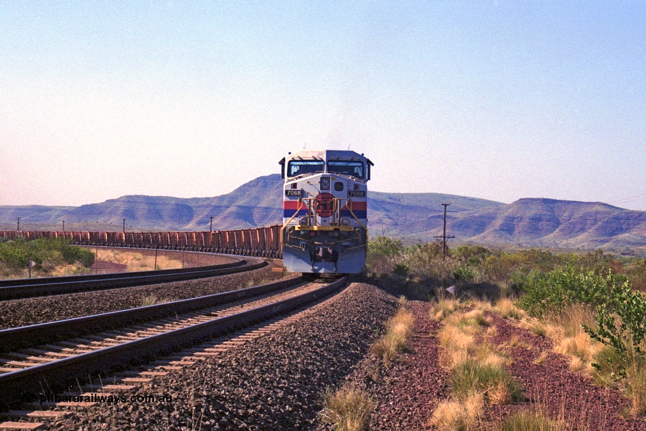 250-15
Pelican Siding on the Hamersley Iron Tom Price line about the 208 km with an empty train behind the standard pairing of two General Electric built 9-44CW units 7068 serial 47747 and 7067 serial 47746 stand on the loop or passing track for a meet with a loaded train. 1550 hrs 21st October 2000.
Keywords: 7068;GE;Dash-9-44CW;47747;