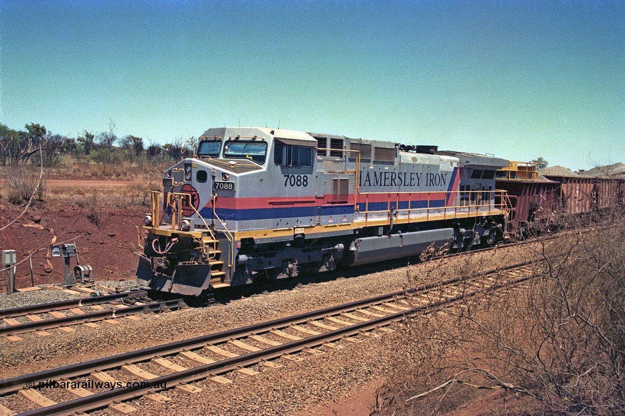 252-03
Cockatoo Siding 273 km on the Hamersley Iron line to Yandi, General Electric built 9-44CW unit 7088 with serial number 47767 from the original 1994 build idles away on the eastern end of the ballast train as it is loaded and slowly progresses into the back track siding Ballast plough BP 02 is behind the locomotive. Location is roughly [url=https://goo.gl/maps/bCvLZxMc1z57F8ym9]here[/url]. 24th November 2001.
Keywords: 7088;GE;Dash-9-44CW;47767;